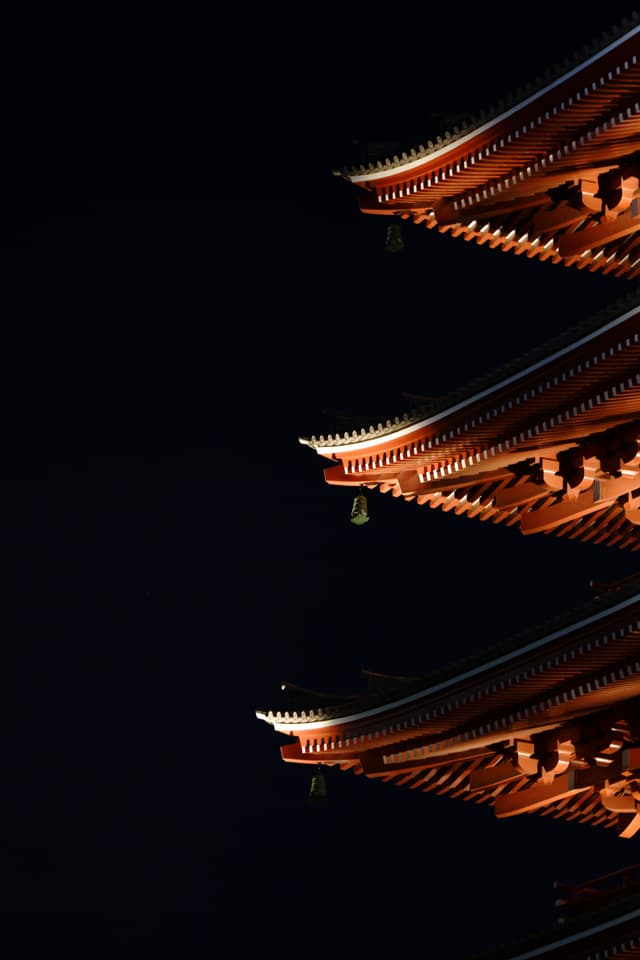 夜空下的传统建筑屋檐，灯光照亮了精致的木质结构。