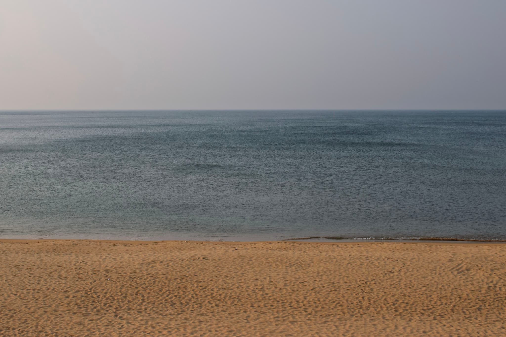 沙滩与大海相接,海水平静,天空晴朗。